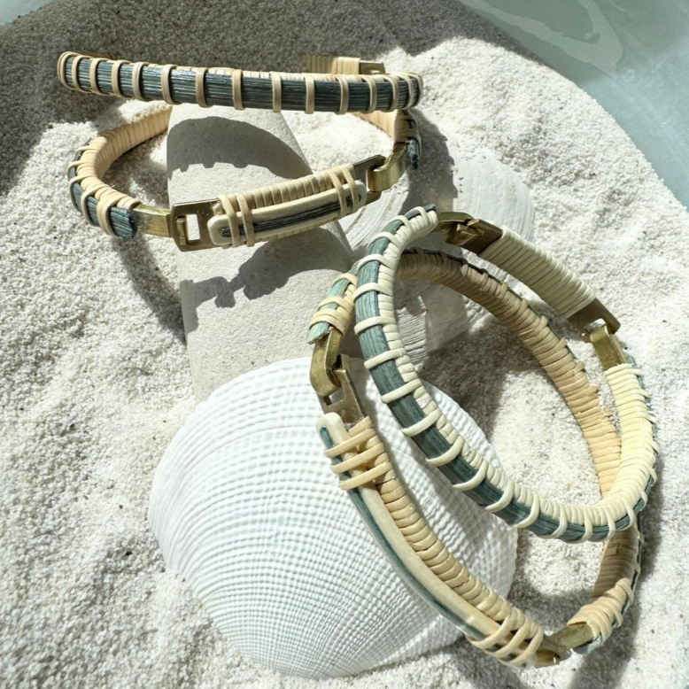 Woven hoop clasp bracelets with light bluwin center in bowl of sand with a shell