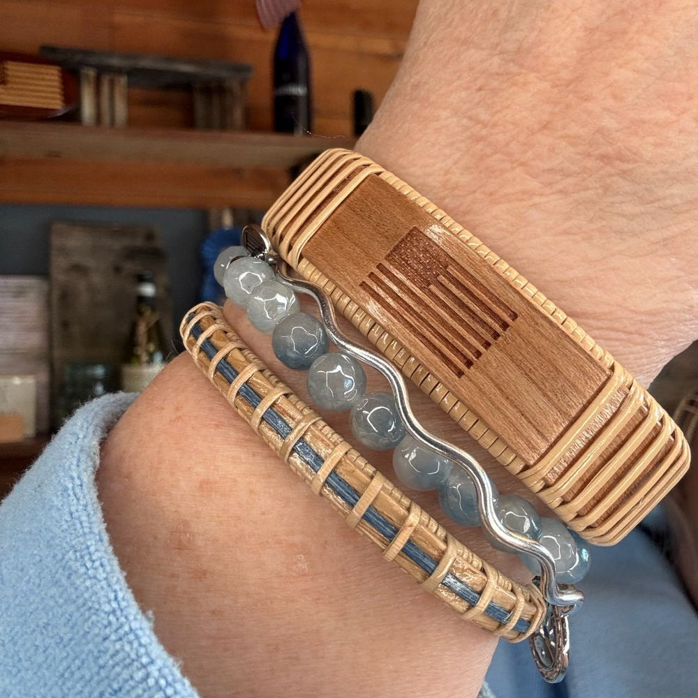 Wooden bracelet with metal components on a wrist, blurred indoor background