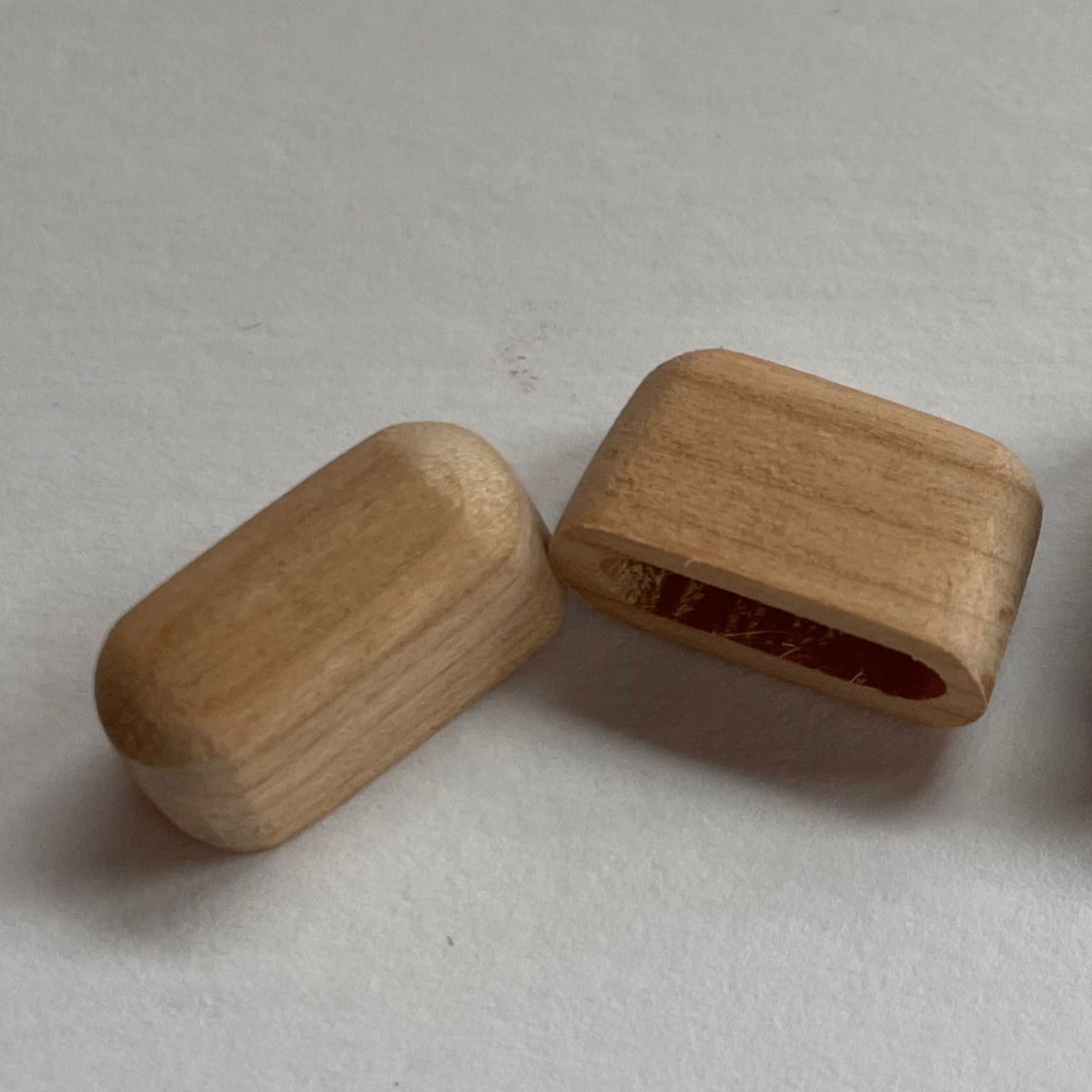 Two wooden end caps on a light background, one cap showing the natural wood color and the other with a red-brown stain.