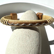 Drift by Stonington Designs handcrafted cuff in cherry wood with a sterling silver wave accent, displayed on a natural stone.