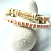 Bloom clasp bracelet in amaryllis orange woven cane displayed on a white stone jewelry holder.