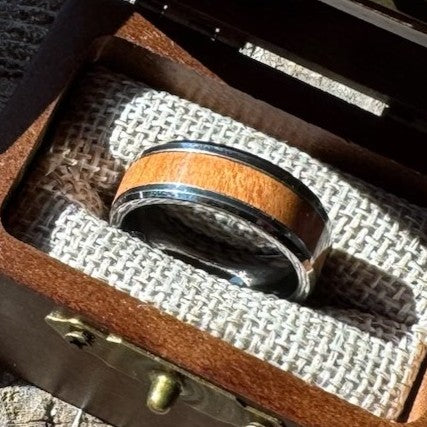 Close-up of a Beacon 8mm tungsten ring with cherry wood inlay resting in an open Drift by Stonington Designs wooden gift box.