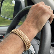 Handcrafted cherry Maverick Cuff Bracelet worn on a man's wrist at a steering wheel, showing the bold wide silhouette as an everyday men's wood bracelet.