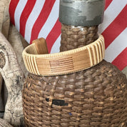 Handcrafted cherry wood Star Spangled cuff bracelet with an etched American flag, resting on a woven basket against a red and white striped flag background.