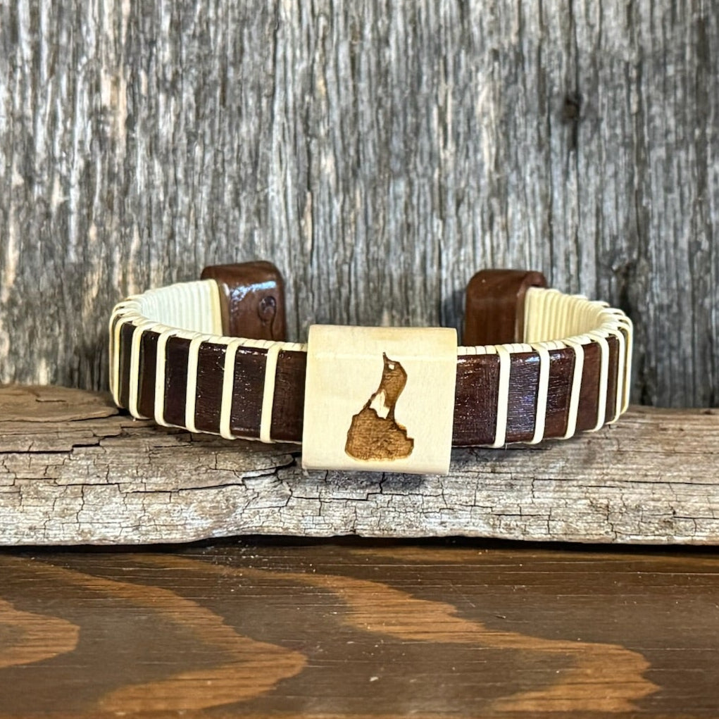 Handcrafted holly wood cuff bracelet with a hand-etched Block Island design on the center bead, displayed on a shell with driftwood in the background — handmade by Military Spouse artisans in Stonington, Connecticut using American-made materials.