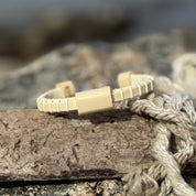 Single holly Cove cuff bracelet with holly slider resting on nautical rope on driftwood.