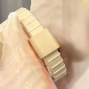 Handcrafted all-holly Island Cuff Bracelet with holly slider bead resting against a large seashell, showing the natural pale wood tones