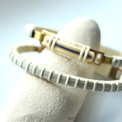Bloom clasp bracelet in hydrangea blue woven cane displayed on a white stone jewelry holder.