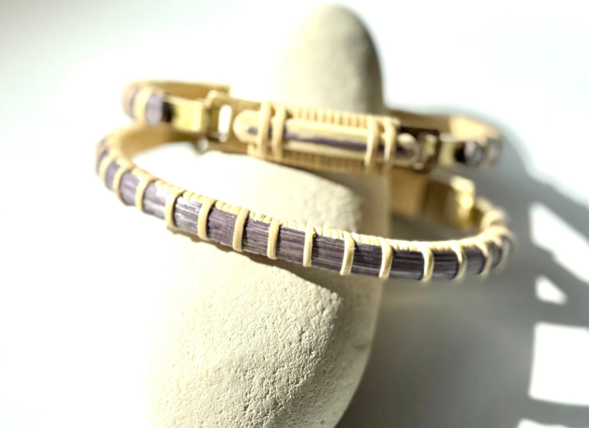 Bloom clasp bracelet in lilac purple woven cane displayed on a white stone jewelry holder.