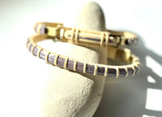 Bloom clasp bracelet in lilac purple woven cane displayed on a white stone jewelry holder.