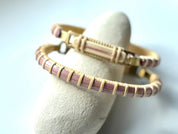 Bloom clasp bracelet in orchid pink woven cane displayed on a white stone jewelry holder.