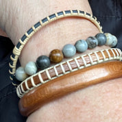 Beachcomber bracelet with Picasso jasper stones and a wood bead worn stacked on a wrist with a cane bangle and wood cuff bracelet.