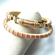 Bloom clasp bracelet in poppy red woven cane displayed on a white stone jewelry holder.