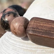 Close-up of tumbled rhodonite stones and a rectangular wood bead on the Beachcomber bracelet.