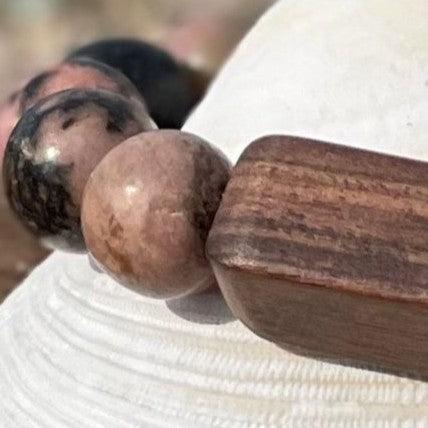 Close-up of tumbled rhodonite stones and a rectangular wood bead on the Beachcomber bracelet.
