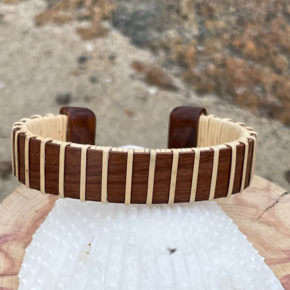 Handcrafted rosewood Maverick Cuff Bracelet resting on a white textured stone, showing the rich dark rosewood stave and holly weave construction.