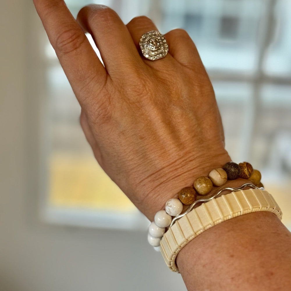 Pebbles stone bracelet in white and brown tumbled beach stones worn stacked on a wrist with a woven cuff bracelet