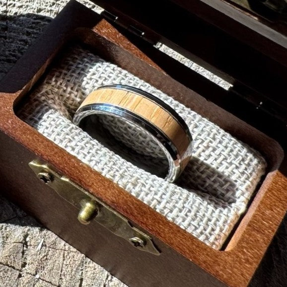 Close-up of a Beacon 8mm tungsten ring with white oak wood inlay resting in an open Drift by Stonington Designs wooden gift box.