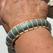 Harbor Mist statement cuff worn on the wrist, showing the hand-dyed blue bamboo weave and cherry end caps in natural light.