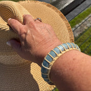 Harbor Mist cuff bracelet worn outdoors with a straw sun hat, overlooking the water on a bright coastal afternoon.