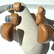Harbor Mist, Tidewater, and Estuary cuff bracelets stacked together, showing the hand-carved cherry end caps of the Marsh Collection