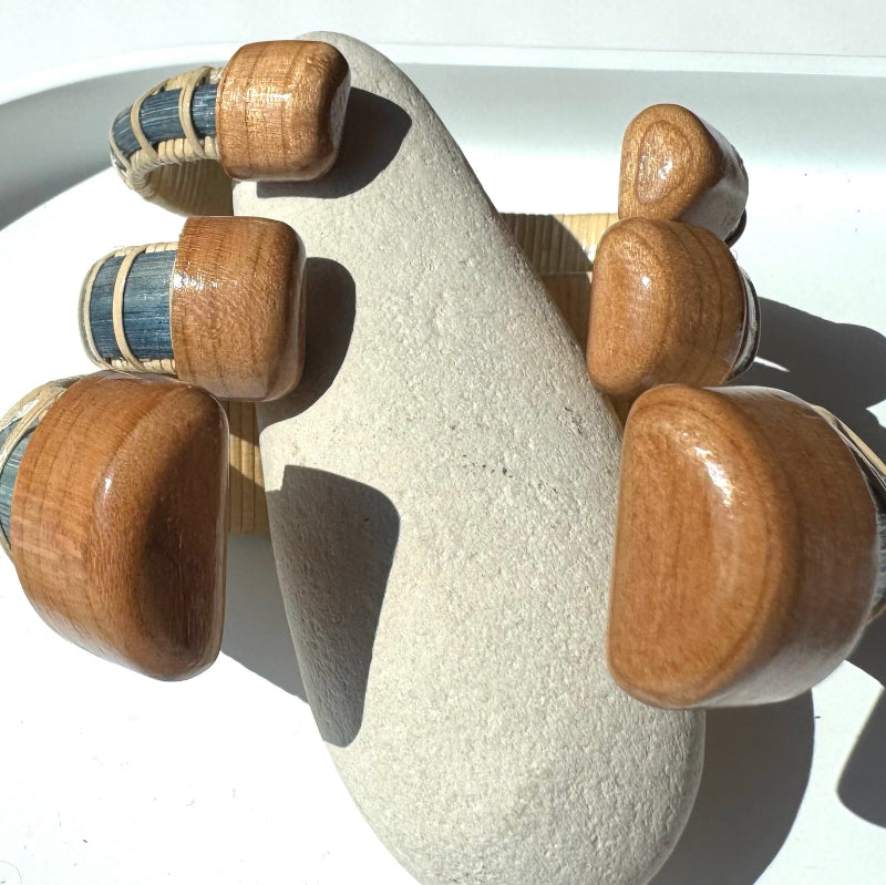 Harbor Mist, Tidewater, and Estuary cuff bracelets stacked together, showing the hand-carved cherry end caps of the Marsh Collection