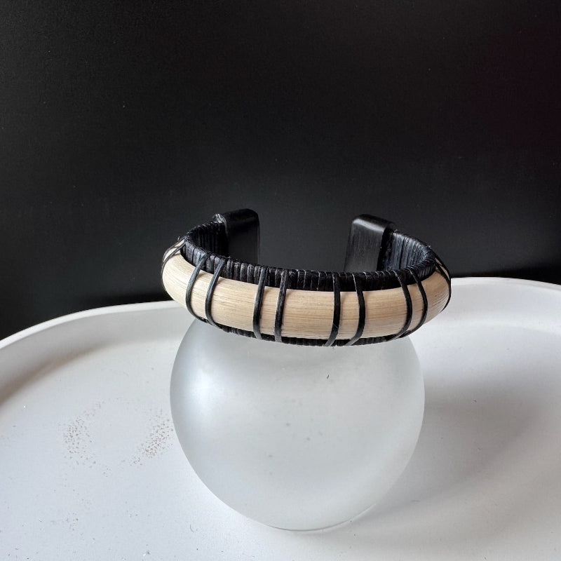 Front view of the Moonbeam wood cuff by Stonington Designs, with black bamboo weaving, a pale stave, and ebony end caps.