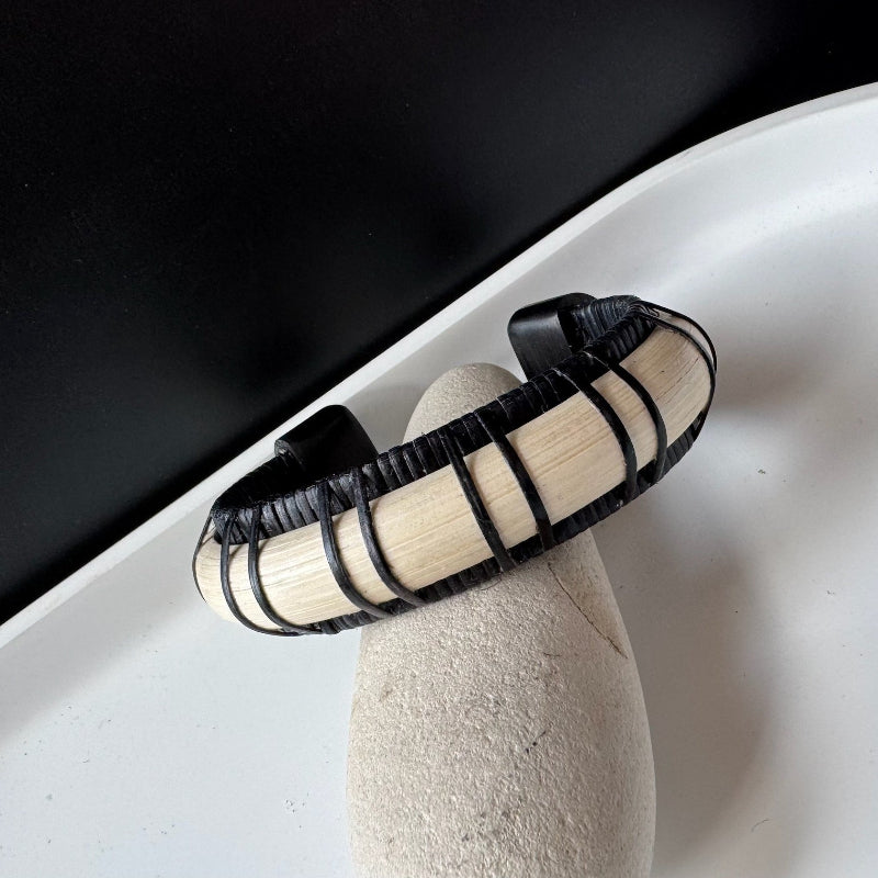 Angled detail of the Stonington Designs Moonbeam cuff, showing black bamboo woven over a pale wood stave and an ebony end cap.