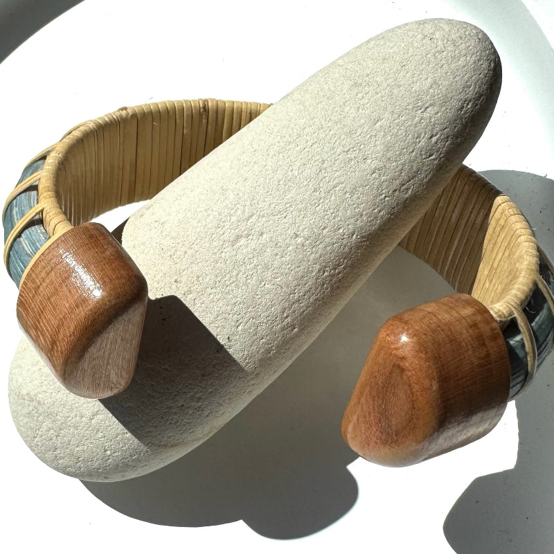 Tidewater statement cuff in hand-dyed blue bamboo, resting on a smooth stone with woven texture in full view.