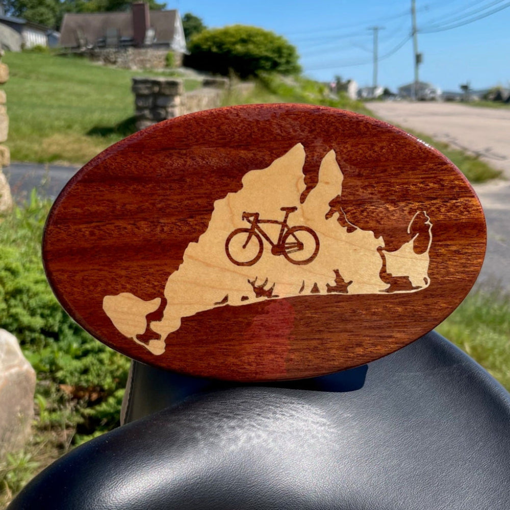 A wooden hitch cover with a maple inlay, designed with a bicycle and the outline of Martha's Vineyard.