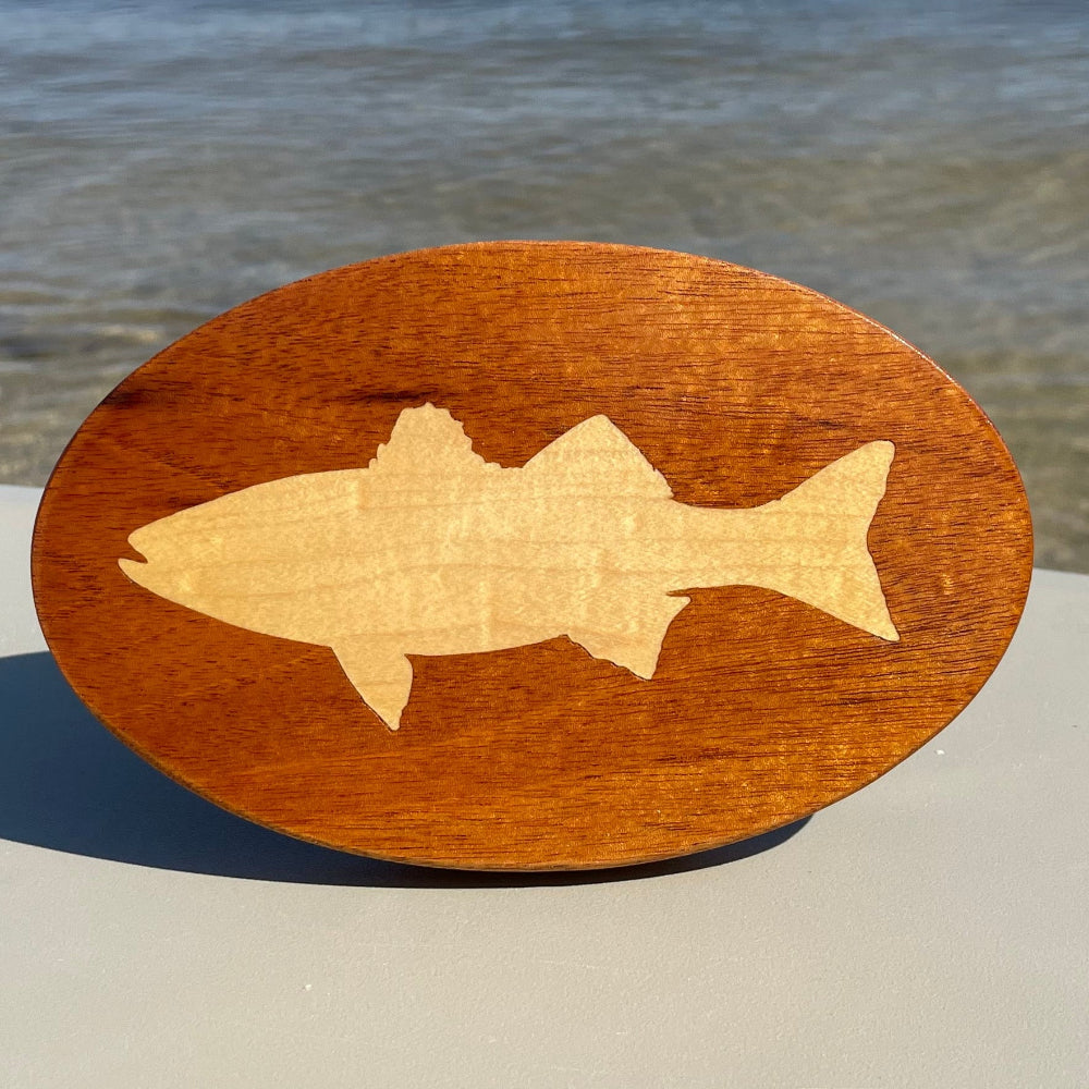 sailfish inlay on a wooden hitch cover in front of water