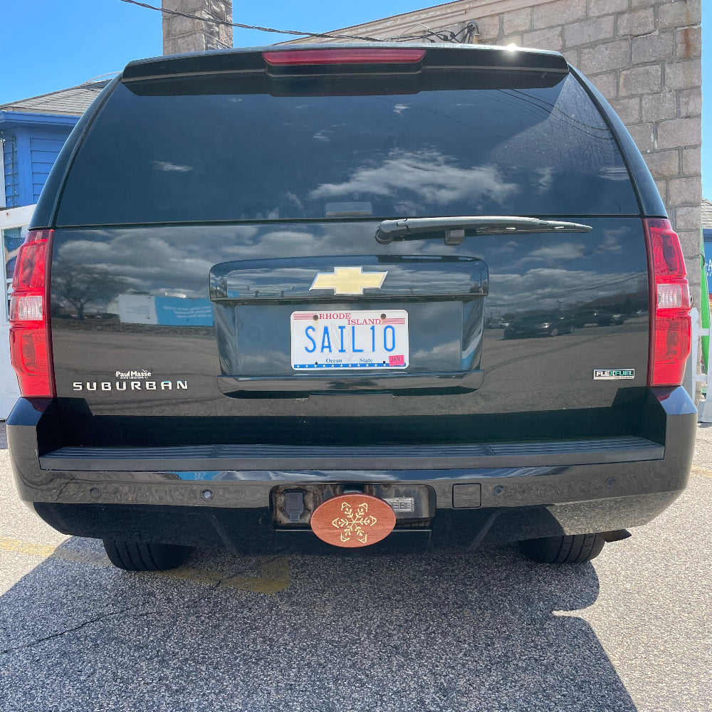 snowflake maple inlay design on a wooden hitch cover on the back of a suburban vehicle