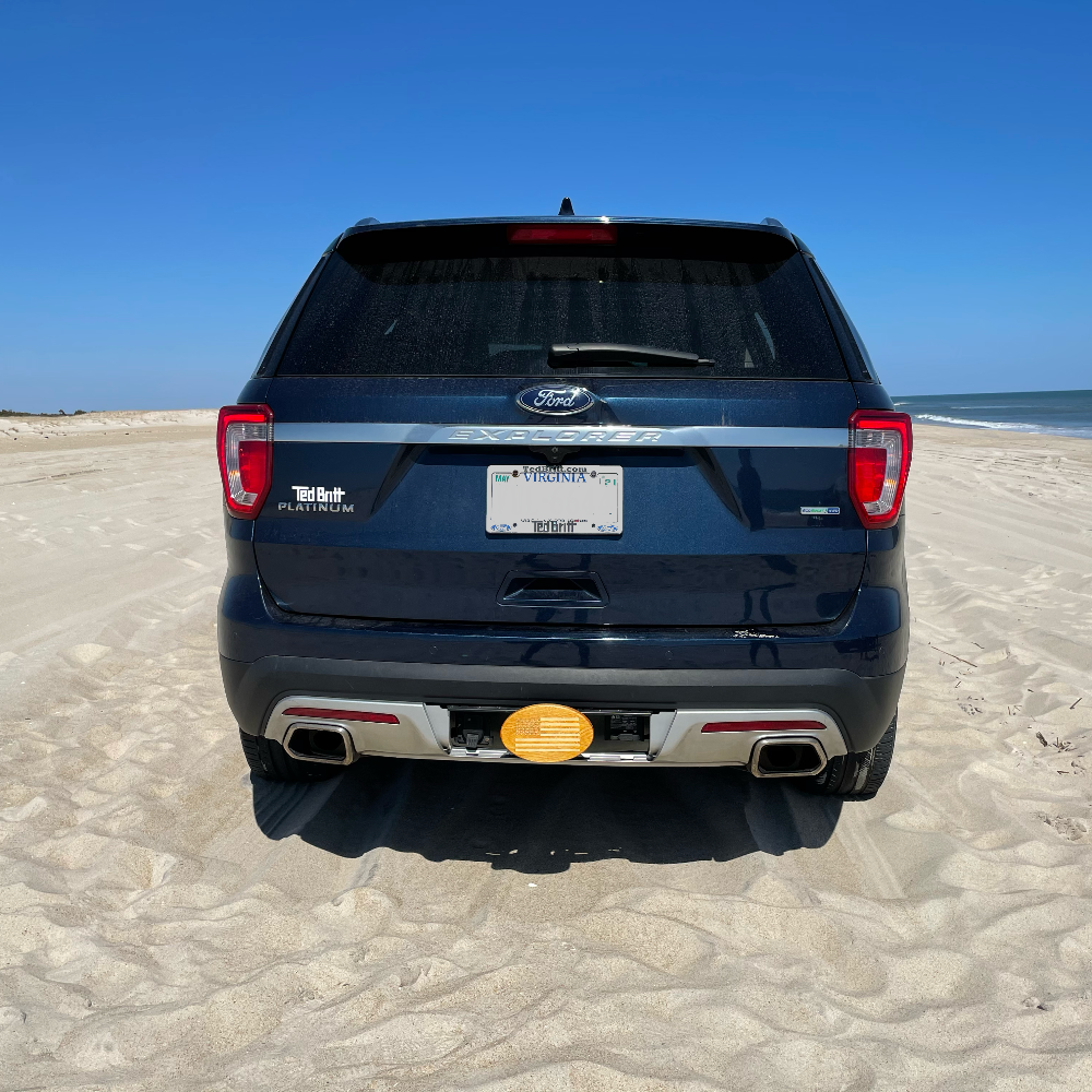 AMerican flag on back of a dark blue truck on the beach