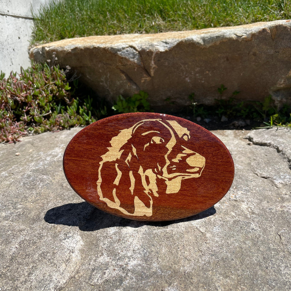 Ginny dog face design on a wood hitch cover balanced on a rock