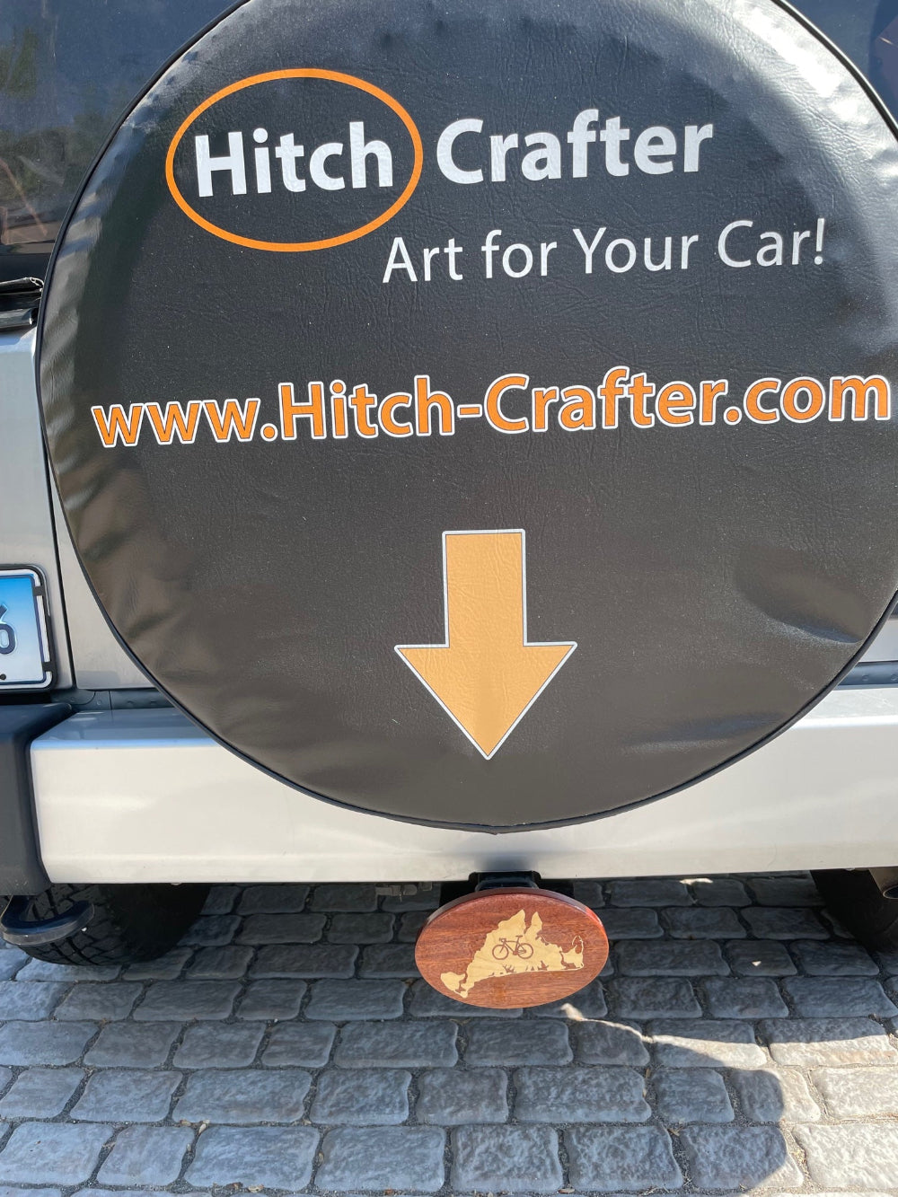 A wooden hitch cover with a maple inlay, designed with a bicycle and the outline of Martha's Vineyard behow logo for Hitch Crafter