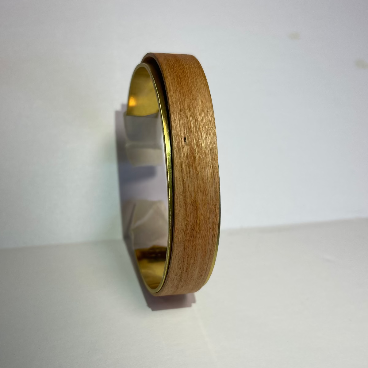 brass cuff and stave leaved up against a wall vertically